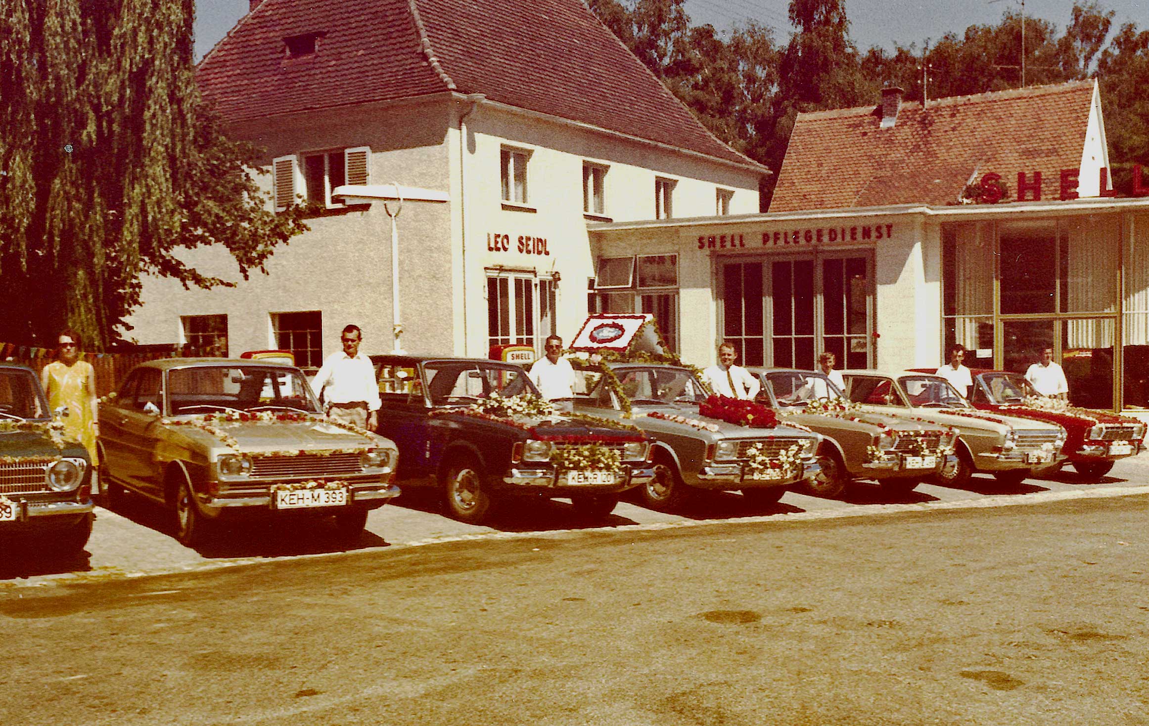 Die mit Blumen geschmückte Ford-Modellpalette. Leider 1967, zwei Jahre vor Erscheinen des Capri, abgelichtet. Die Zapfsäulen des Mineralölkonzerns Shell standen zu diesem Zeitpunkt im Freien (unter der großen Laterne). Die mit Blumen geschmückte Ford-Modellpalette. Leider 1967, zwei Jahre vor Erscheinen des Capri, abgelichtet. Die Zapfsäulen des Mineralölkonzerns Shell standen zu diesem Zeitpunkt im Freien (unter der großen Laterne).
